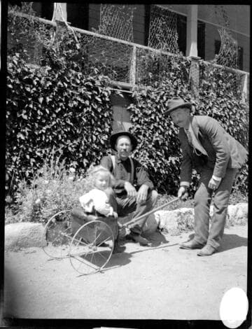 Two men playing with a little girl in a cart