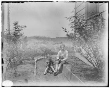 Two young boys in the garden at the side of a house