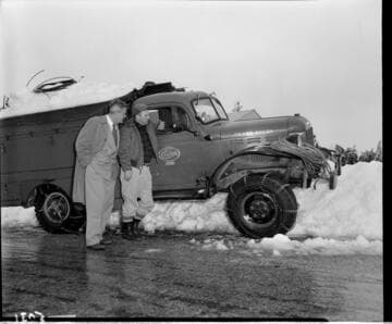 Two men by line truck with snow chains on all wheels