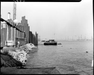 Man standing at water's edge near cable crossing at Long Beach Harbor