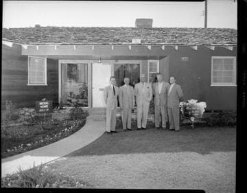Opening of housing tract with model home selling for $20,500, with group gathered in front of house. with 1 variant