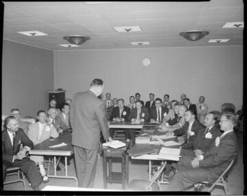 Group of men in a meeting, and roast on spit cooking under infra-red lights