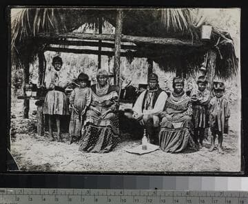 Seminole Indians in front of palmetto hut in Everglades
