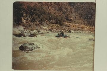 10-man inflated boat dropping into the head of Disaster Falls.  Bus Hatch is at the oars and Edward Tuttle rides as passenger