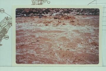 Jean and Hal Bennett in Rapid #22 in Cataract Canyon.  Print from dupe owned by the Bennetts.  10,430 cfs.  Compare with Davis photo Roll 6 #3 of 1953, July 10, showing change in rocks on shore