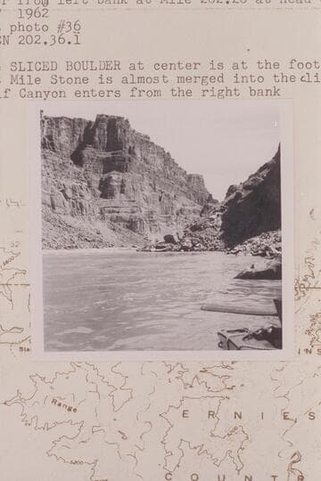 Up river from left bank at Mile 202.20 at head of Rapid #23.  The Sliced Boulder at center is at foot of rapid No. 22.  303 Mile Stone is almost merged into cliff in distance.  Calf Canyon enters from the right bank