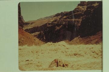 Wave at head of Hance Rapid piling over the boulder which is exposed near the left bank in low water
