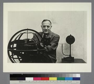Edwin Powell Hubble, seated with his cat Nicolas Copernicus, behind an armillary sphere