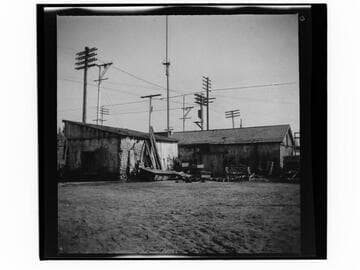 Dilapidated adobe buildings with piles of objects next to them in unidentified city