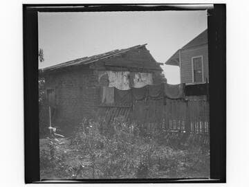 Small adobe building next to newer house