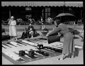 Woman rolling giant dice in giant backgammon game, Santa Monica