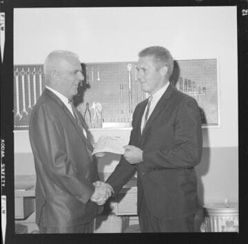Men reviewing certificates of completion for auto mechanics training