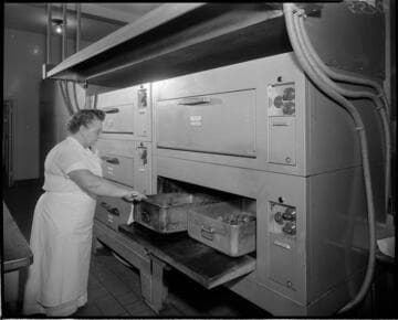 Chef checking roasting pans in commercial ovens