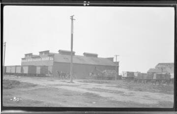 Side view of a packing house in Exeter showing pack horses carrying packages in the foreground