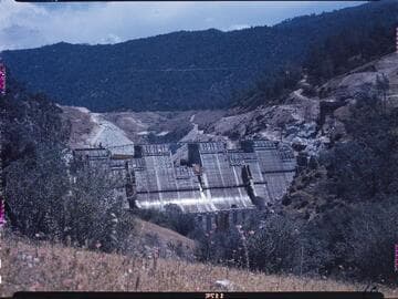 Big Creek #4 project: Shot looking down on Dam 7, over half complete, with red flowers in the foreground