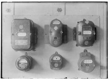 Six electric meters mounted in a group.  All are different designs