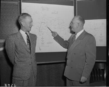 Two men reviewing map on wall