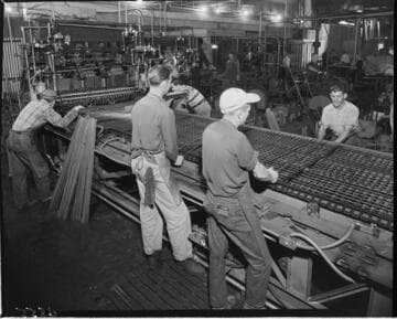 Men on assembly line making metal pallets