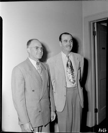 Two men standing against wall