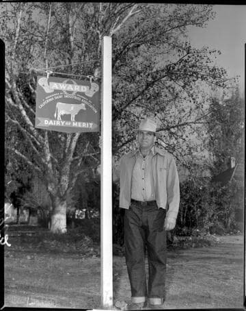 Dairy owner standing by award sign
