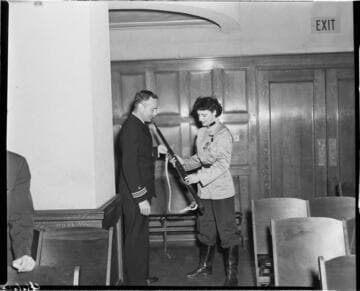Man and woman in uniform exchanging a rifle