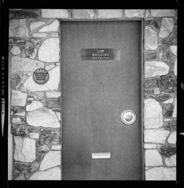 All Electric Building plate displayed on stone wall next to Law Building door