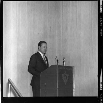 Speaker giving a presentation on stage at the Statler Hilton Hotel