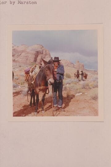 Toby Owl (Nasja Begay) prepares to unsaddle at camp in the upper end of Wilson Creek.  Dan Lehi in the distance