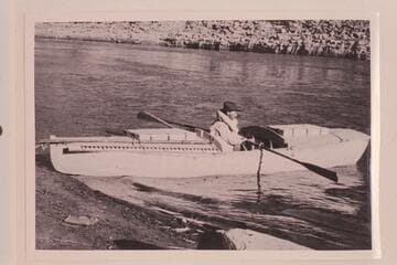 Ellsworth Kolb in boat used by USGS in survey of Cataract Canyon in 1921, Sep.  Narrow beam was a handicap to stability.  The forward bulkhead is so near the oarsman that he cannot make a full stroke of the oars.  In Cataract Canyon
