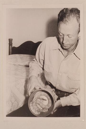 Lorin Bell. Taken in the Boulder Dam Hotel immediately following the Nevills first Grand Canyon run in 1938. He exhibits in the can a white rattlesnake which he caught somewhere along the river and kept as a pet for some time thereafter