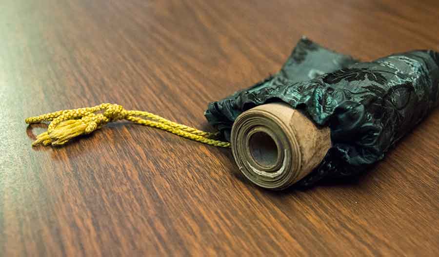 In the Middle Ages, the tiny roll was most likely carried in a leather pouch. For several decades, however, it has been kept in this Victorian silk purse with golden drawstrings. Photograph by Kate Lain. In the Middle Ages, the tiny roll was most likely carried in a leather pouch. For several decades, however, it has been kept in this Victorian silk purse with golden drawstrings. Photograph by Kate Lain.