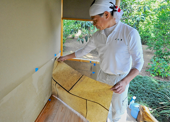 Yamada removes the old, faded rice paper from the machiai. Photo by Andrew Mitchell.